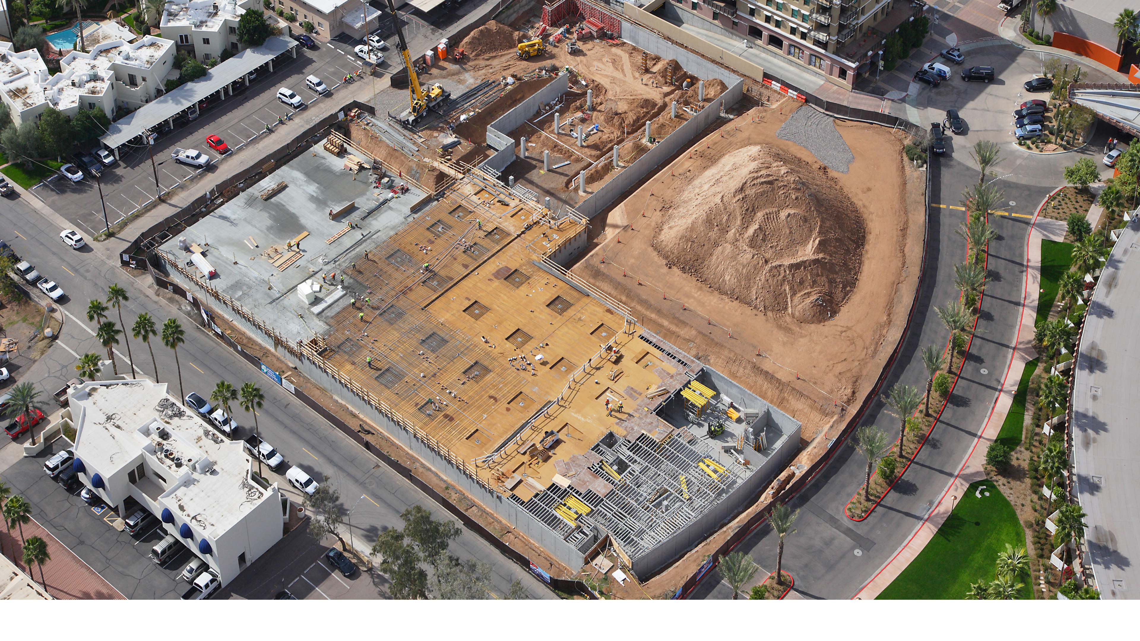 multifamily podium construction aerial showing concrete structure and site work Scottsdale Arizona
